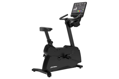 Black upright stationary exercise bike with digital console display, padded seat, handlebars, and stabilizing base on white b
