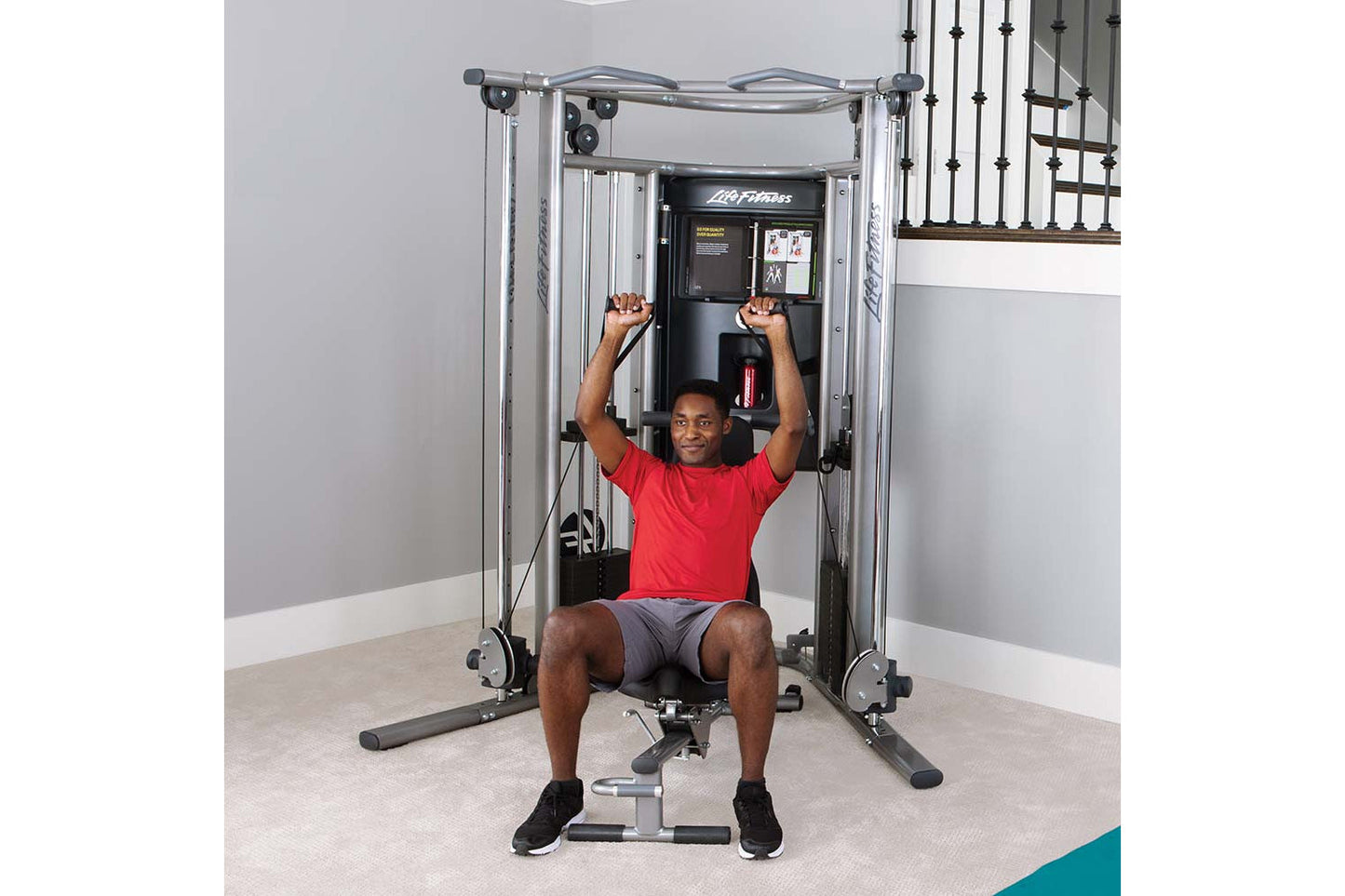 Man in red shirt using silver and black Life Fitness G7 home gym machine with cable arms raised overhead