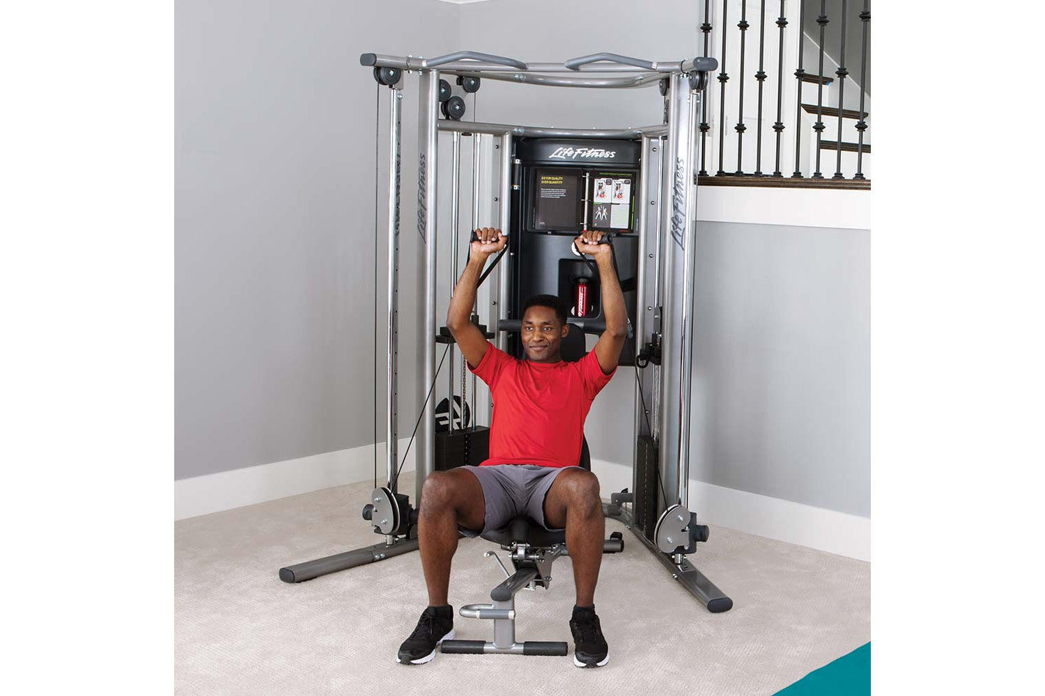 Man in red shirt using silver and black Life Fitness G7 home gym machine with cable arms raised overhead