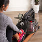 Woman using black water rower with digital display on wooden floor, wearing gray top and pink sneakers