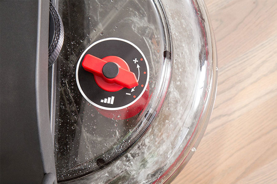 Red and black water rower damper control dial with white icon, mounted on clear water tank with water droplets visible
