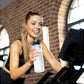 Woman on a stationary bike holding a water bottle in a gym setting