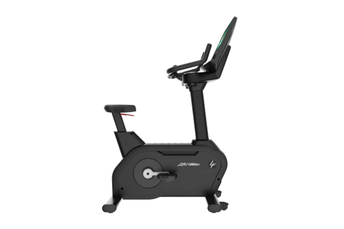 Black upright exercise bike with padded seat, fixed handlebars, and digital display on white background