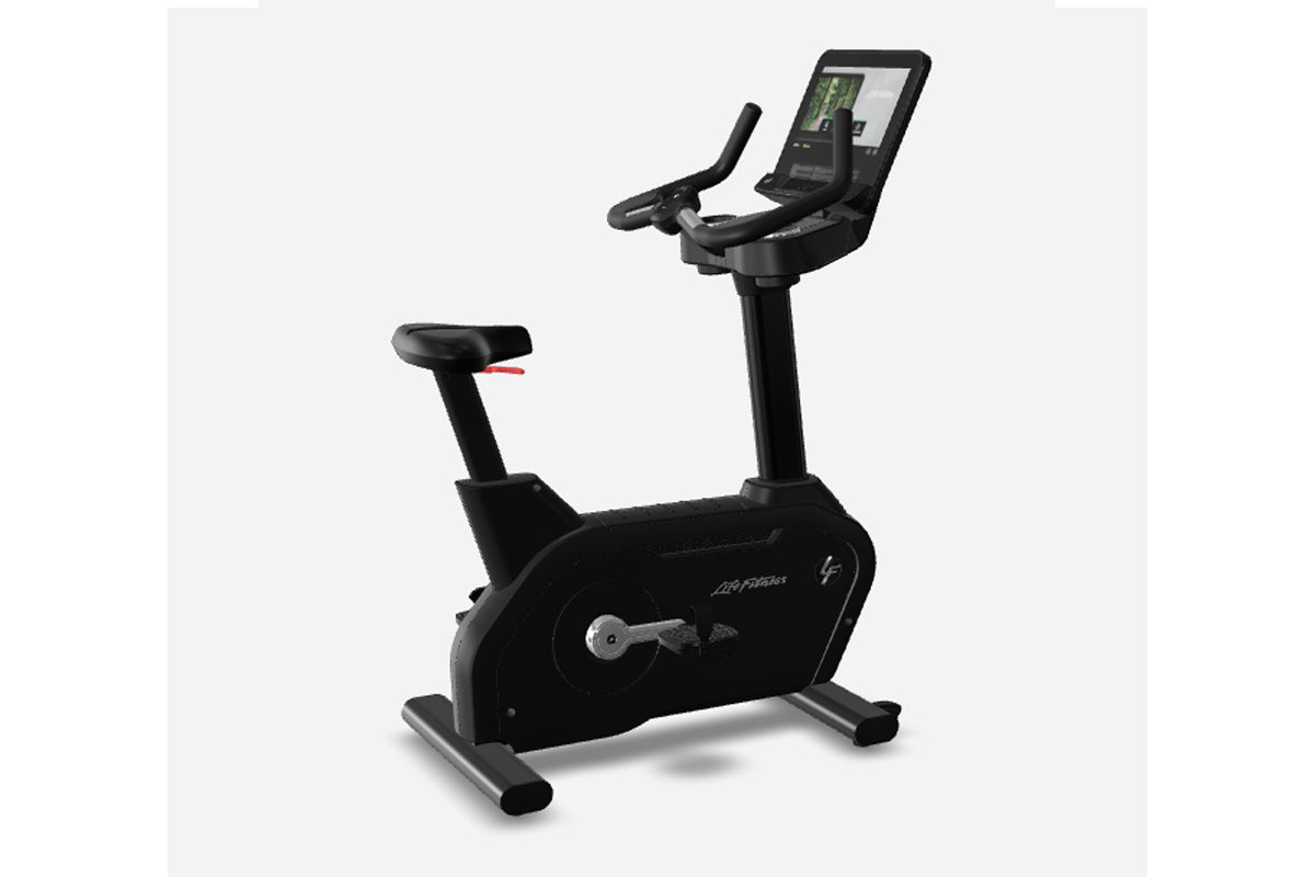 Black upright exercise bike with digital touchscreen display, padded seat, handlebars, and foot pedals on gray background