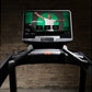 Life Fitness Integrity+ treadmill with black frame and touchscreen display showing fitness app interface against brick wall