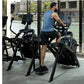 Man wearing blue sleeveless tank top using black Life Fitness arc trainer elliptical machine in gym with city view windows