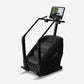 Black stair climber machine with digital display console and handlebar grips on white background