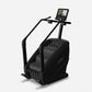 Black stair climbing exercise machine with digital console display and handlebar grips on white background
