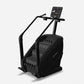 Black stair climber machine with digital console, dual handles, and textured foot pedals on white background