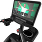 Black and gray stationary climber machine with digital touchscreen displaying fitness workout app and instructor in white shi