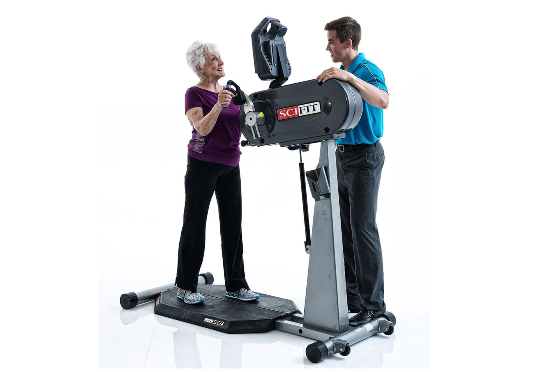 SCIFIT PRO1 Sport standing upper body ergometer with gray frame and black cylindrical resistance unit, demonstrated by two us