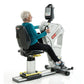 Senior woman using white and black SCIFIT PRO1000 upper body exercise machine with digital display monitor on white backgroun