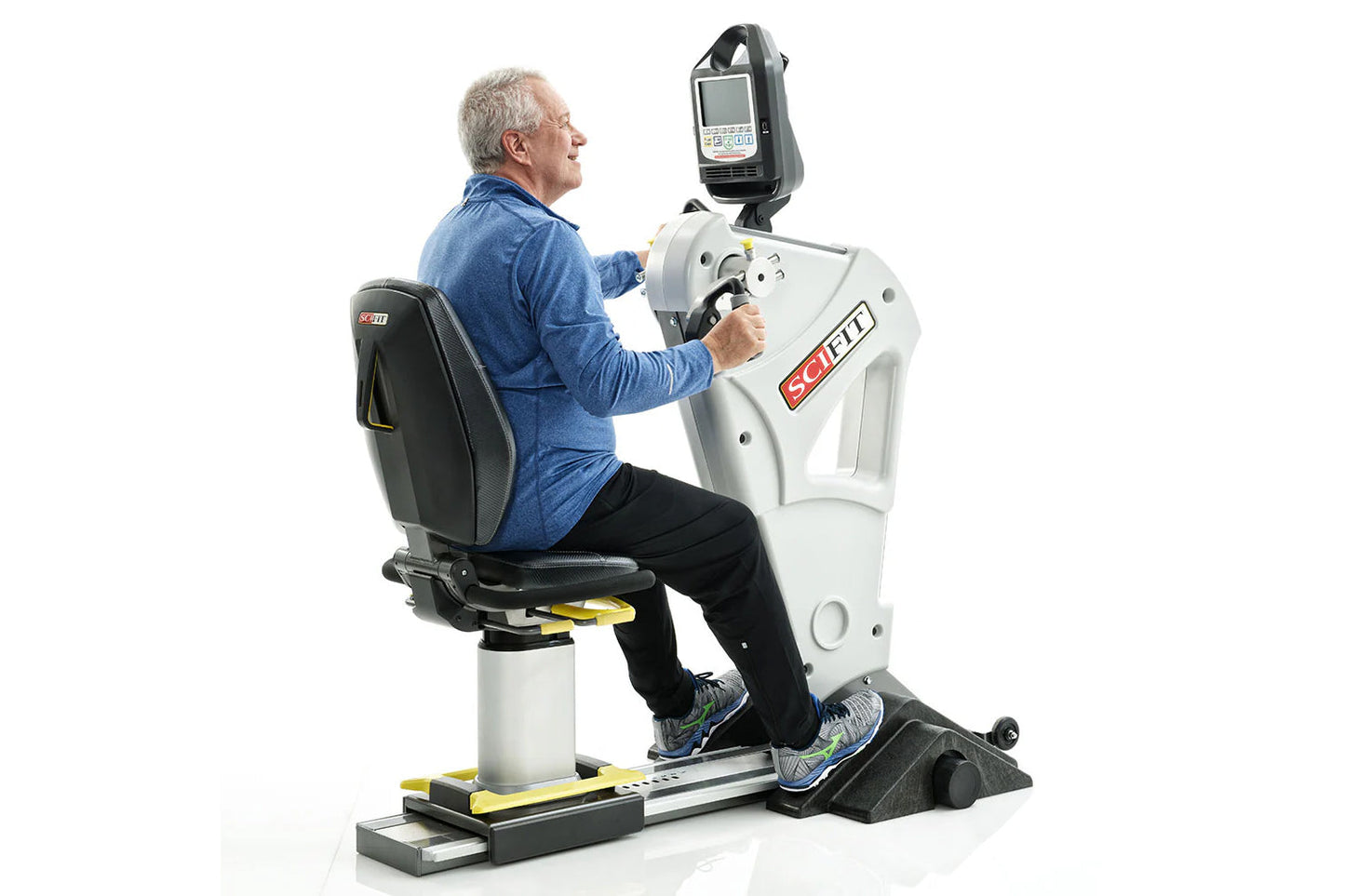 Older man in blue shirt using white and black SCIFIT upper body exercise machine with digital display monitor, seated positio