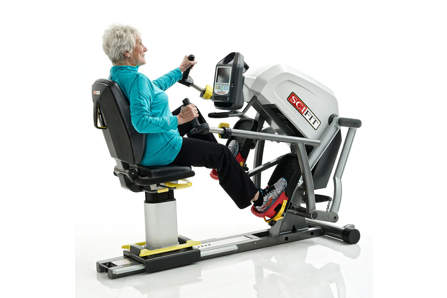 Older adult using SCIFIT StepOne recumbent stepper with white and gray frame, holding handles while exercising, white backgro