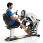 Man in blue shirt using white and black recumbent stepper machine with digital display, on white background