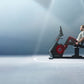 Man wearing beige t-shirt and burgundy pants seated on Life Fitness Symbio red and black recumbent exercise bike against blue