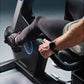 Man wearing smartwatch and dark compression tights on Life Fitness Symbio recumbent exercise bike with blue accent lighting
