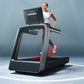 Woman in white tank top and burgundy leggings running on black and silver Life Fitness treadmill with digital display against