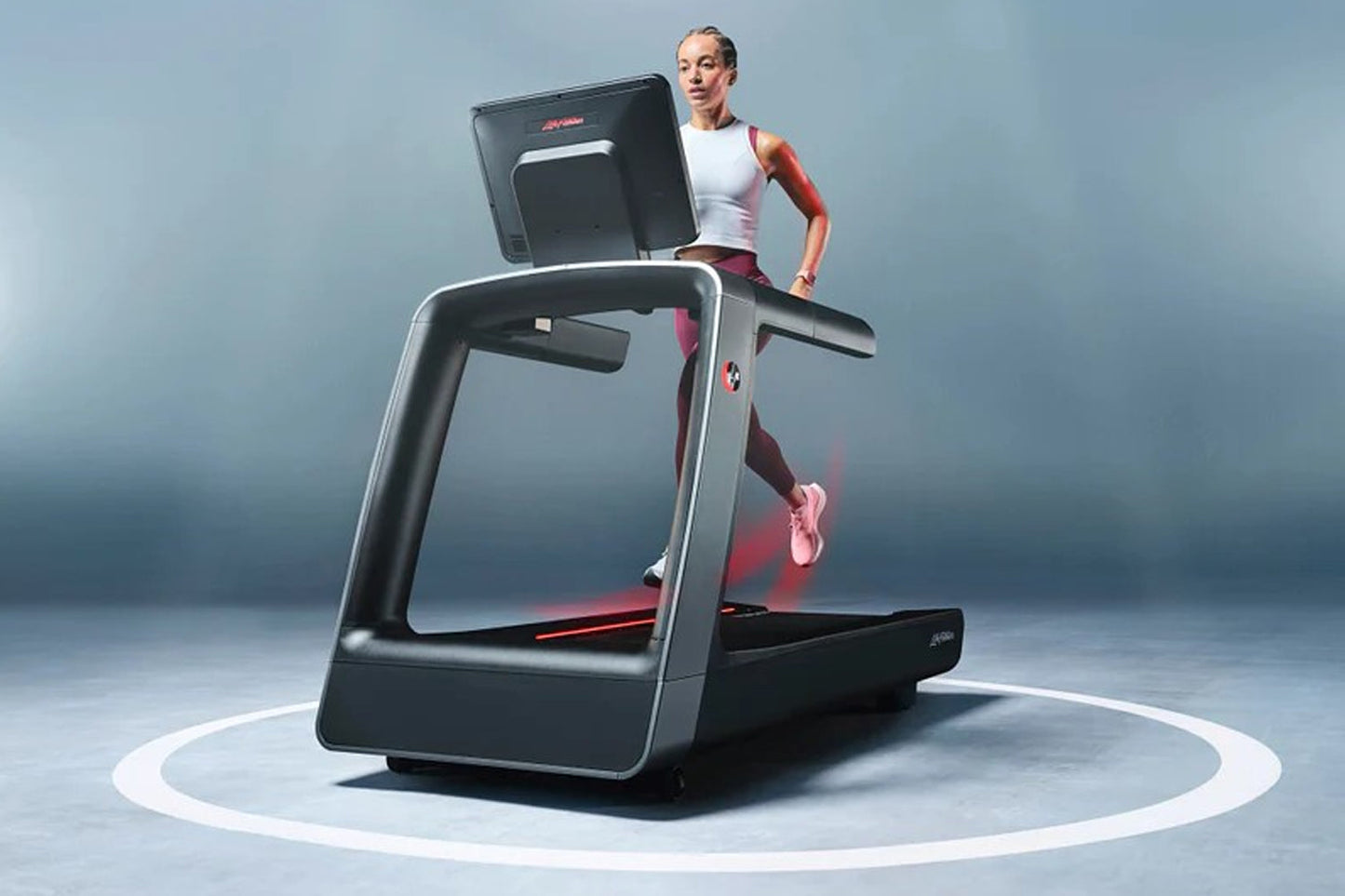 Woman in white tank top and burgundy leggings running on black and silver Life Fitness treadmill with digital display against