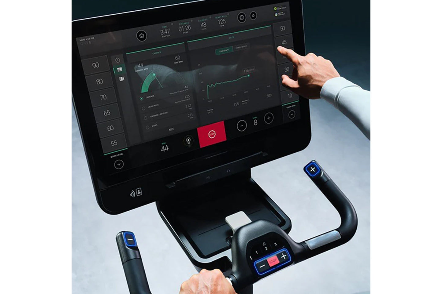 User interacting with Life Fitness Symbio Switch stationary bike, displaying digital dashboard with fitness metrics and teal-