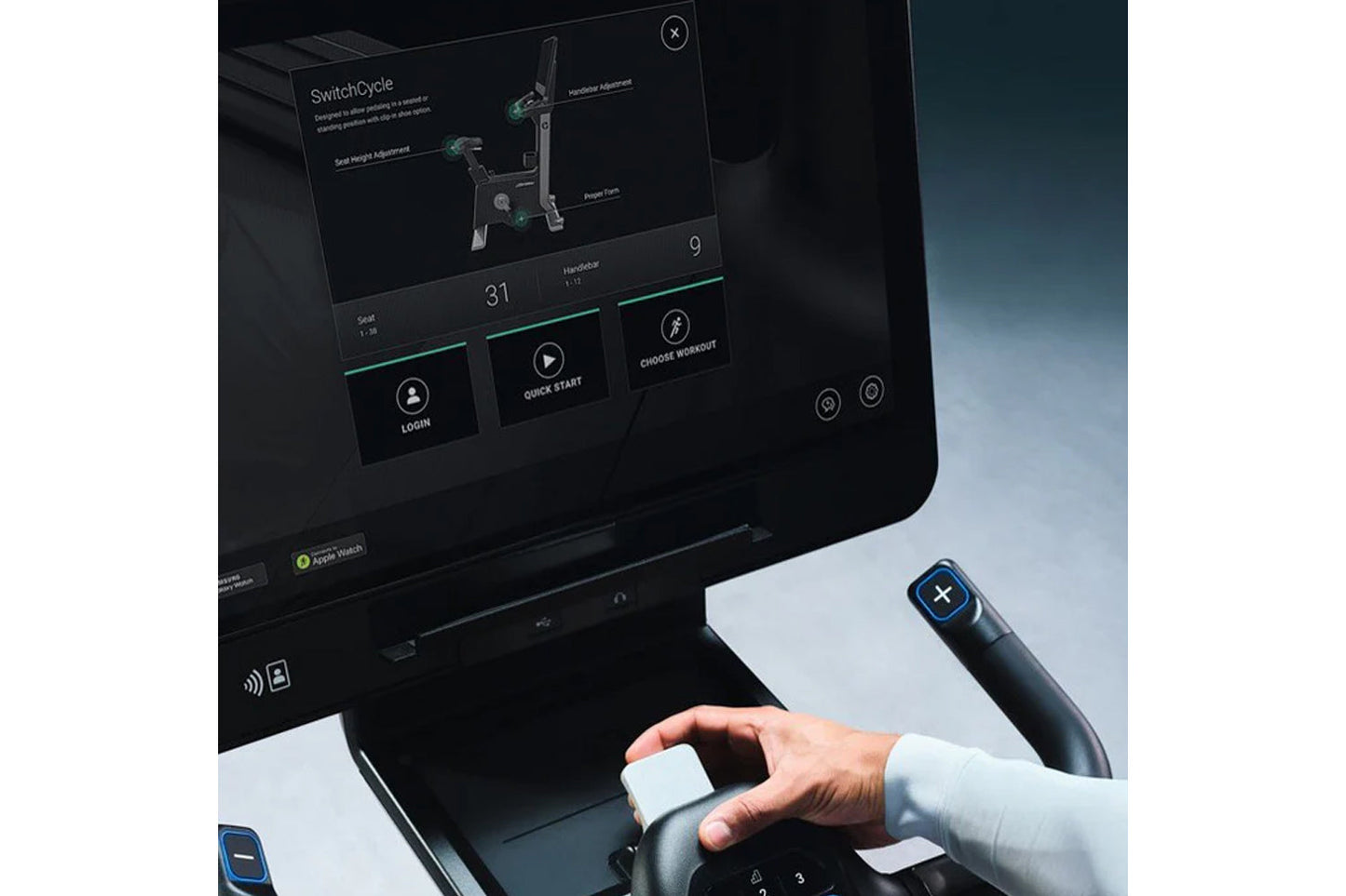 Life Fitness Symbio stationary exercise bike with tablet display showing SwitchCycle workout app, held by person in white sle