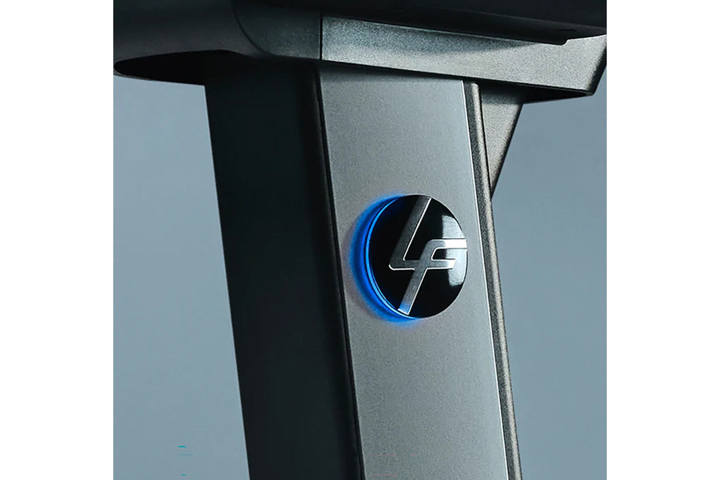 Silver and black stationary bike frame with blue illuminated logo detail on side panel