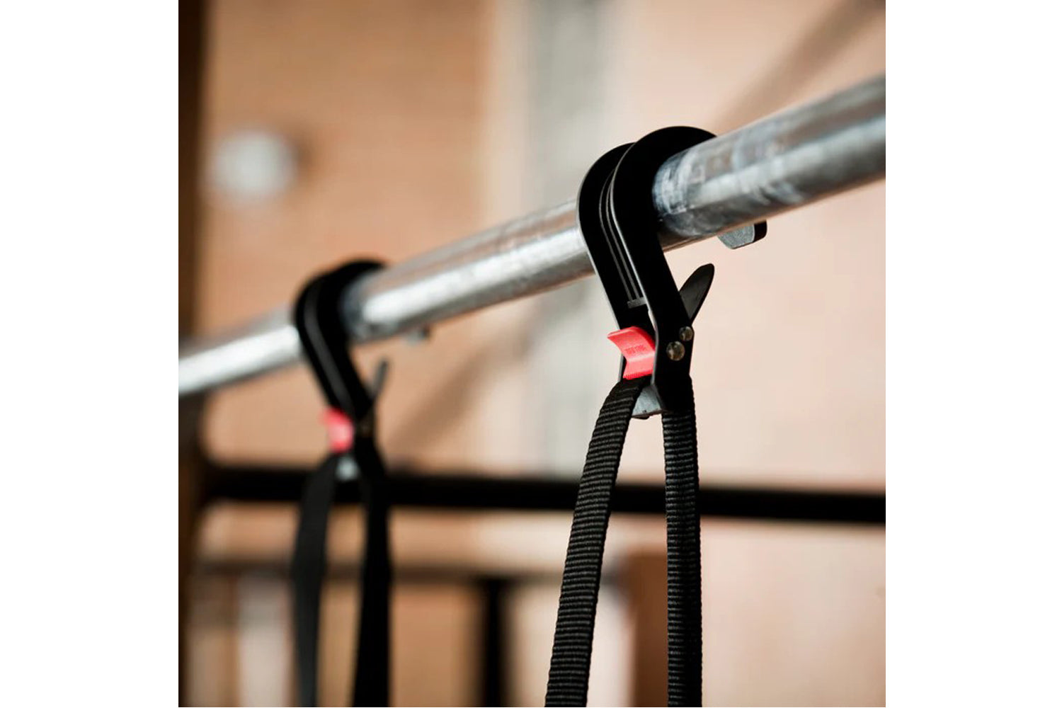 Black pull-up assist band with red buckle clipped to metal pull-up bar, showing elastic resistance strap