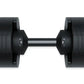 Pair of black adjustable dumbbells with textured grip plates, metal connecting bar, and weight markings on handles on white b