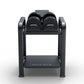 Black adjustable dumbbell storage rack with two pairs of rounded dumbbells on upper tier and flat base platform, on white bac