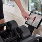 Person viewing fitness workout on tablet next to black adjustable dumbbells on windowsill