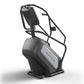 Matrix Endurance ClimbMill with black frame, gray seat, and upper body handles on white background