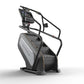 Matrix Endurance ClimbMill with black frame, gray seat, digital display console, and dual climbing handles on white backgroun