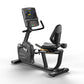 Black Matrix recumbent exercise bike with digital console display, padded seat, and foot pedals on white background
