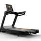 Black commercial treadmill with digital touchscreen display, gray running belt, and orange accent trim on white background