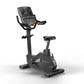 Matrix Endurance upright exercise bike with black frame, digital display console, handlebars with gold accents, and padded se
