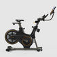Matrix ICR50 black indoor exercise bike with gold accents, digital display console, and tablet holder, on white background