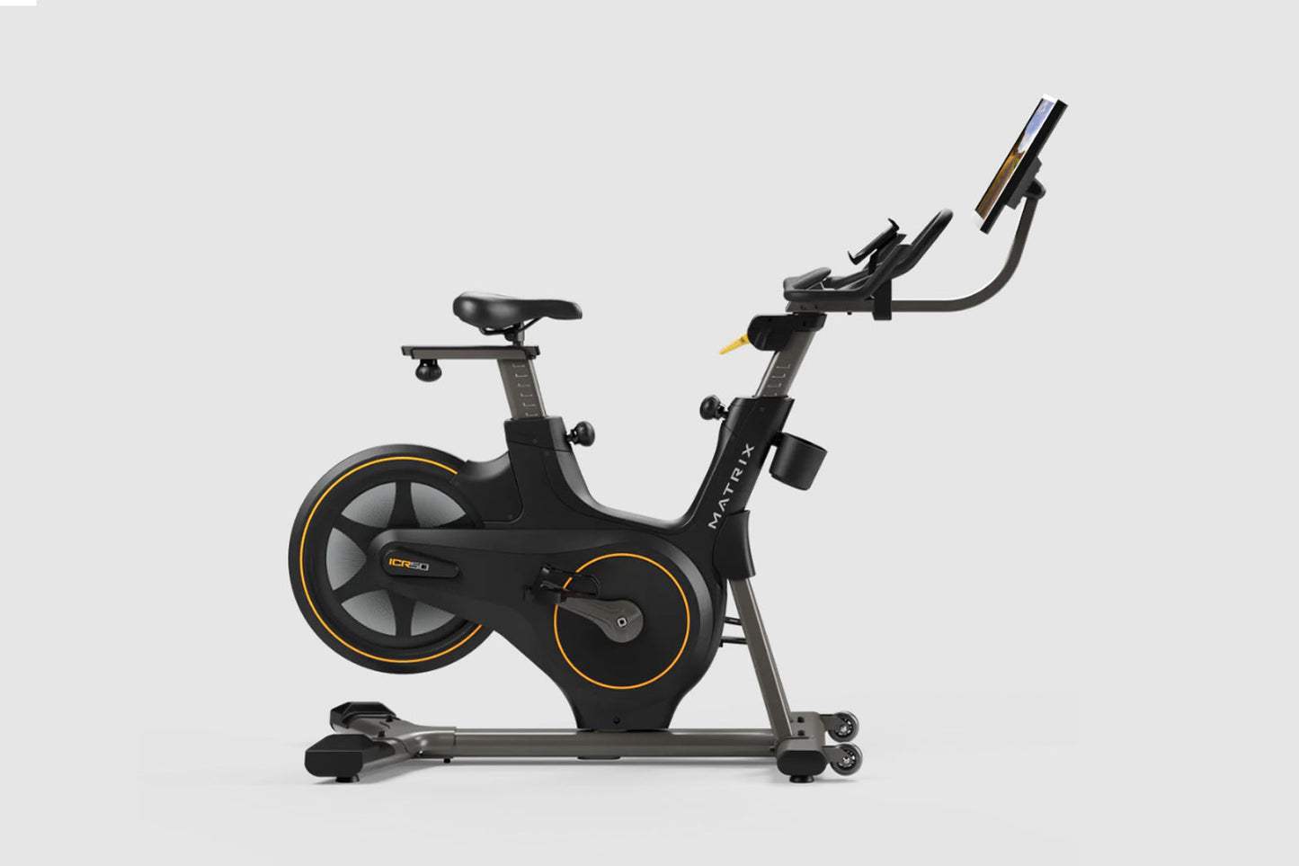 Matrix ICR50 black indoor exercise bike with gold accents, digital display console, and tablet holder, on white background