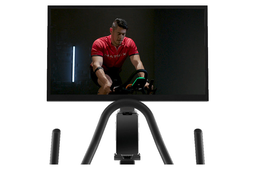 Matrix ICR50 stationary exercise bike with black frame and curved handlebar, console display showing cyclist in red shirt