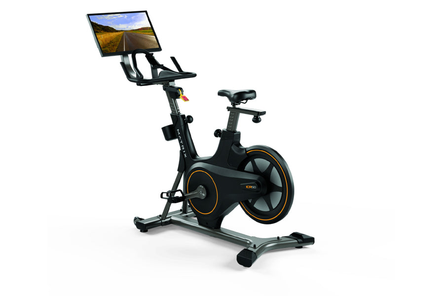 Black stationary exercise bike with orange accents, tablet console mounted on handlebar displaying road scenery, on white bac