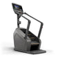 Black and gray commercial stair-climbing machine with digital console display and handrails on white background