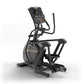 Black and gray elliptical machine with digital display console, dual handles, and footrest on white background