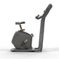 Matrix Lifestyle upright exercise bike with black frame, padded seat, vertical handlebar post, and gold accent trim on white 