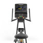 Black upright exercise bike with digital console displaying sprint metrics, dual handles, and gray padded seat on white backg