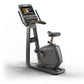 Matrix black upright exercise bike with touchscreen display, handlebar grips, pedals, and cushioned seat on white background