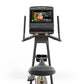 Matrix black upright exercise bike with touchscreen console displaying fitness class, dual handles, and pedals on white backg