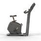 Matrix Lifestyle upright exercise bike with black frame, padded seat, handlebar display, and gold accents on white background