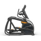 Black and dark gray elliptical trainer with orange accents, featuring adjustable handlebars and foot pedals, on white backgro