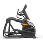 Black and orange elliptical trainer with dual handles and foot pedals on white background