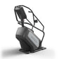 Black and gray Matrix ClimbMill stair climbing exercise machine with handrails and digital display on white background