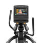 Black Matrix elliptical machine with touchscreen display showing workout video interface, dual handles with yellow grips, and